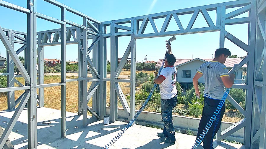 Workers assembling a light steel structure frame on-site using prefabricated components produced by LGSF technology.